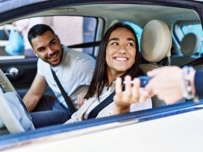 Zweitwagen versichern: Junge Fahrerin erhält Autoschlüssel durchs Seitenfenster gereicht