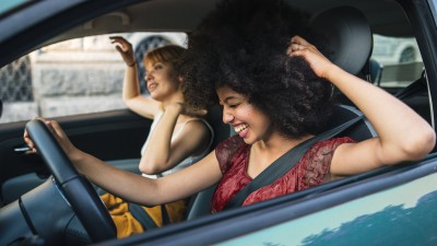 Zwei Frauen sitzen in einem Auto und lachen