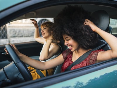 Zwei Frauen sitzt in einem Auto und lachen