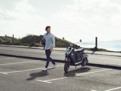 Rollerversicherung: Junger mann parkt seinen E-Motorroller