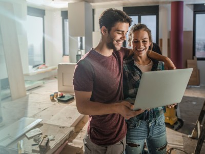 Bauherrenhaftpflicht: Junges Paar mit Laptop auf Baustelle
