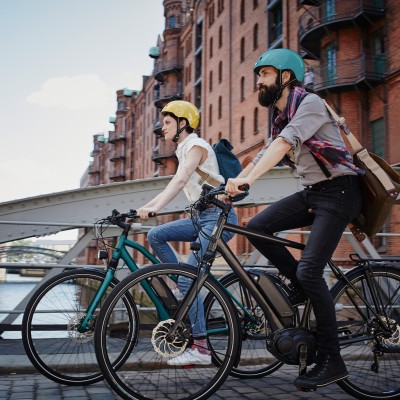 Fahrradversicherung: Zwei Menschen fahren mit ihren Farrädern über eine Brücke