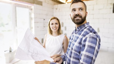Bauherrenversicherung: Paar mit  Bauplan im Rohbau 