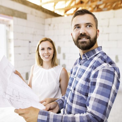 Bauherrenversicherung: Paar mit  Bauplan im Rohbau 
