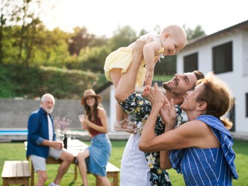 Junge Familie fröhlich mit Baby im Garten