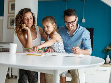 Junge Familie mit Kind malen zusammen ein Bild an einem Tisch