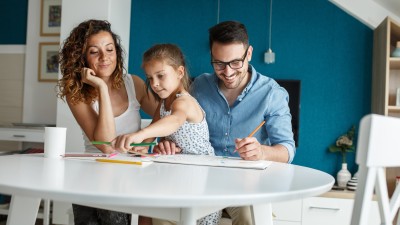 Junge Familie mit Kind malen zusammen ein Bild an einem Tisch