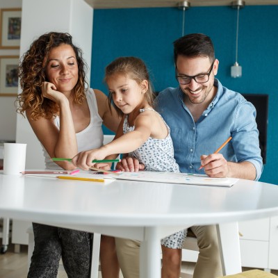 Junge Familie mit Kind malen zusammen ein Bild an einem Tisch