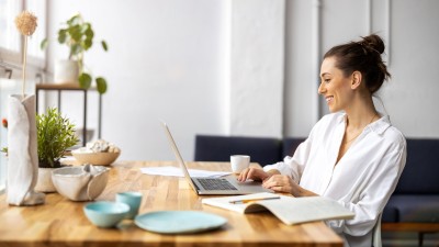 Junge Frau sitzt mit Laptop am Tisch 