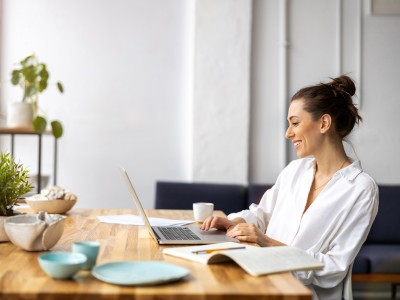 Junge Frau sitzt mit Laptop am Tisch 
