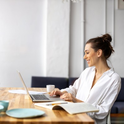 Junge Frau sitzt mit Laptop am Tisch 