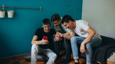 Drei junge Männer schauen gemeinsam auf ein Smartphone