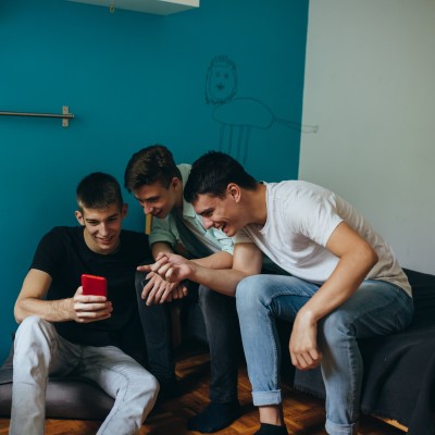 Drei junge Männer schauen gemeinsam auf ein Smartphone