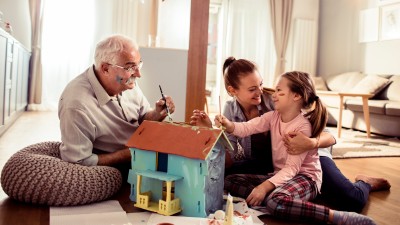 Familie bastelt an einem Modellhaus im Wohnzimmer