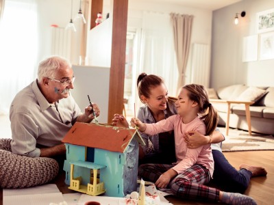 Familie bastelt an einem Modellhaus im Wohnzimmer