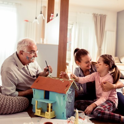 Familie bastelt an einem Modellhaus im Wohnzimmer