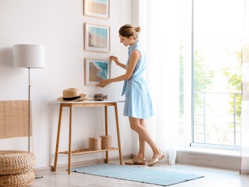 Eine Frau hängt ein Bild auf