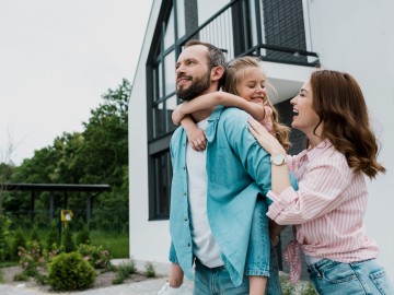Junge Familie mit Kind steht vor ihrem neuen Zuhause