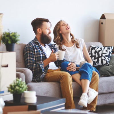 Ein Paar sitzt auf der Couch, um sie herum stehen viele Umzugskartons