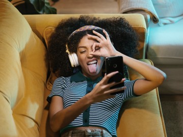 Versicherungen für junge Leute: Junge Frau schneidet vor Handy Grimassen