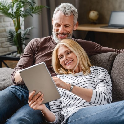 Auszahlung & Wiederanlage der Lebensversicherung: Paar mit Tablet auf dem Sofa