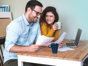 Paar mit Dokumenten und Laptop am Esstisch