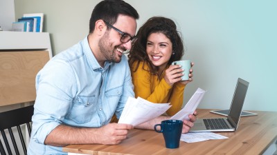 Paar mit Dokumenten und Laptop am Esstisch