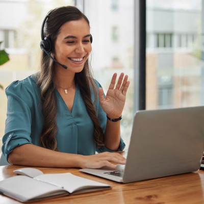 Eine Frau mit Headset vor einem Laptop bei einer Videokonferenz