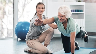 Wellness & Gesundheit: Eine Fitnesstrainerin coacht eine ältere Frau