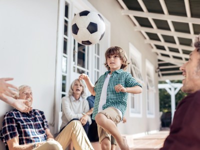 Private Haftpflichtversicherung: Familien schaut einem Kind beim Fussball jonglieren zu