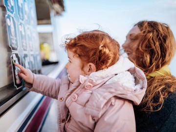 Kind sucht sich beim Eisverkäufer ein Eis aus