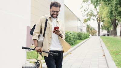Mann schiebt sein Fahrrad und schaut auf sein Smartphone