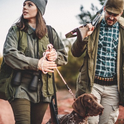 Jagdhaftpflichtversicherung: Junge Frau und Mann laufen mit ihrem Hund im Wald