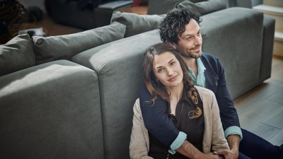 Private Krankenversicherung: Junges Paar sitz auf dem Boden vor der Couch