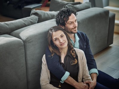 Private Krankenversicherung: Junges Paar sitz auf dem Boden vor der Couch