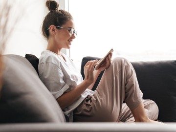 Junge Frau mit Ihrem Smartphone auf dem Sofa