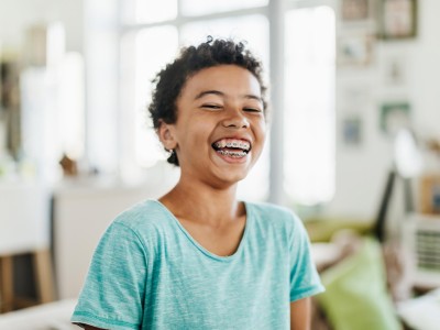 Zahnzusatzversicherung für Kinder & Jugendliche: Lachender Junge mit Zahnspange