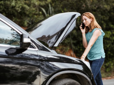 Mobilitätsschutz-Versicherung: Frau mit Autopanne ruft mit Smartphone Hilfe