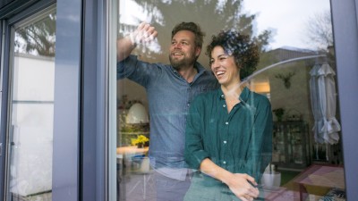 Hausrat- & Gebäudeversicherung: Paar steht vor einem Fenster in einem Haus