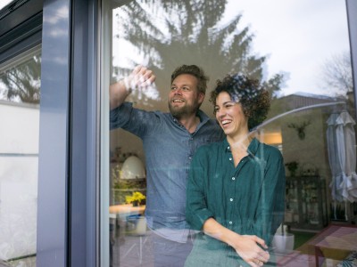 Hausrat- & Gebäudeversicherung: Paar steht vor einem Fenster in einem Haus