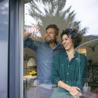 Hausrat- & Gebäudeversicherung: Paar steht vor einem Fenster in einem Haus