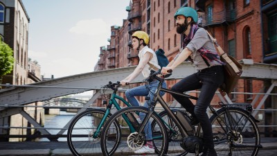 Fahrradversicherung - FahrradPlus : Zwei Menschen fahren mit ihren Farrädern über eine Brücke