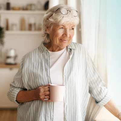 Sterbegeldversicherung & Bestattungsvorsorge: ältere Dame mit einer Tasse in ihrer Küche