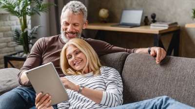 Auszahlung & Wiederanlage der Lebensversicherung: Paar mit Tablet auf dem Sofa